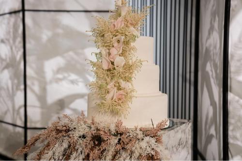 a three tiered white wedding cake with flowers on it at The St. Regis Abu Dhabi in Abu Dhabi