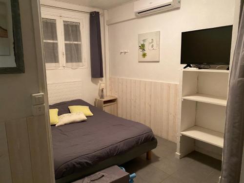 une petite chambre avec un lit et une télévision à écran plat dans l'établissement Hyères studio les pieds dans l eau Au Grand Sud, à Hyères
