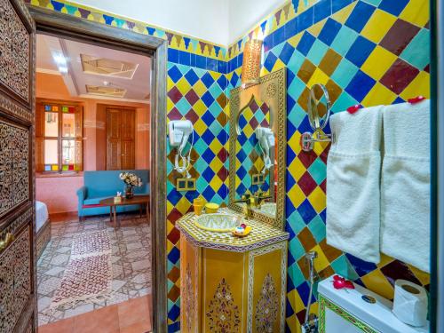 La salle de bains colorée est pourvue d'un lavabo et d'un miroir. dans l'établissement Castle d'Atlas Riad & Spa, à Marrakech
