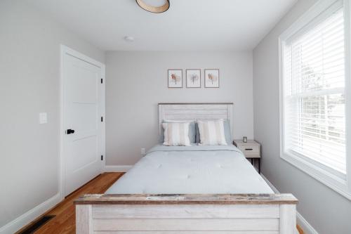 a white bedroom with a bed and two windows at Rest in Westerly in Westerly