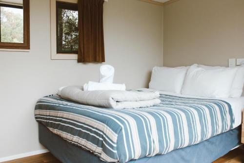 a bedroom with a bed with towels on it at The Barn Cabins & Camp in Marahau
