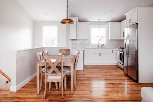 a kitchen with white cabinets and a wooden table and chairs at Rest in Westerly in Westerly