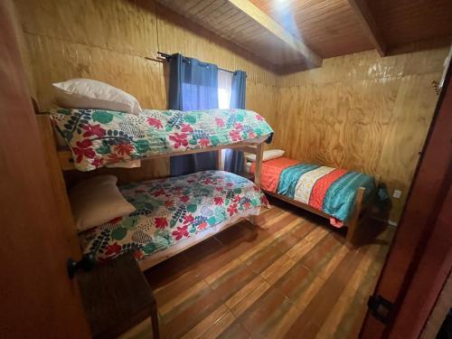 Habitación con 2 literas y suelo de madera. en Cabaña Lago Ranco, puerto nuevo, en Puerto Nuevo