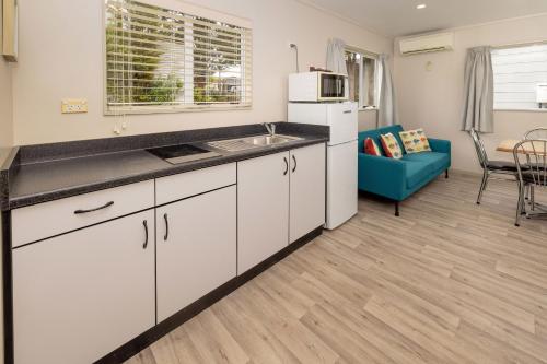 a kitchen with white cabinets and a blue couch at Ohakune TOP 10 Holiday Park in Ohakune