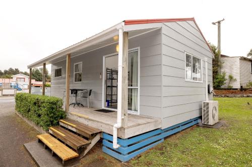 a tiny house with a porch and a bench at Ohakune TOP 10 Holiday Park in Ohakune