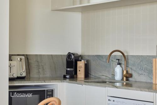 a kitchen counter with a sink and a microwave at Bluewater on the Beach in Byron Bay