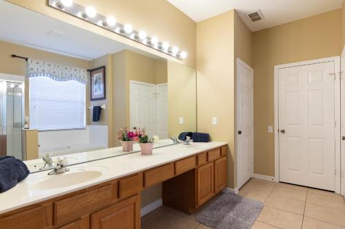 La salle de bains est pourvue d'un lavabo et d'un grand miroir. dans l'établissement Windsor Hills Resort 6 Bedroom Private Pool & Spa 2 Miles to Disney A Villa Can See Disney Fireworks Every Night, à Kissimmee