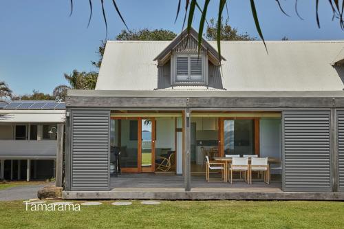 a house with a deck with a table and chairs at Bluewater on the Beach in Byron Bay