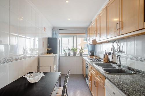 a kitchen with wooden cabinets and a black counter top at Apartamento em Lisboa, perto de Sintra in Fontainhas