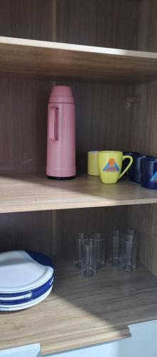 a shelf with plates and cups and a pink appliance at Casa Temporada em Embu das Artes in Embu