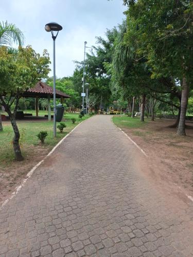 a brick path in a park with trees and a light pole at Casa Temporada em Embu das Artes in Embu