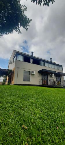 a building with a grass field in front of it at Pousada e Vinícola Boutique Bégamo - Vale dos vinhedos in Bento Gonçalves