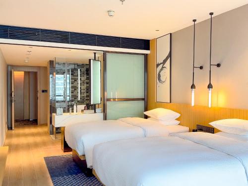 a hotel room with three beds and a bathroom at Fairfield by Marriott Changsha Tianxin in Changsha