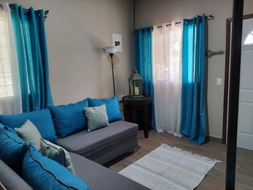 sala de estar con sofá azul y cortinas azules en La Casita del Lago en El Jaral, en Santa Cruz de Yojoa