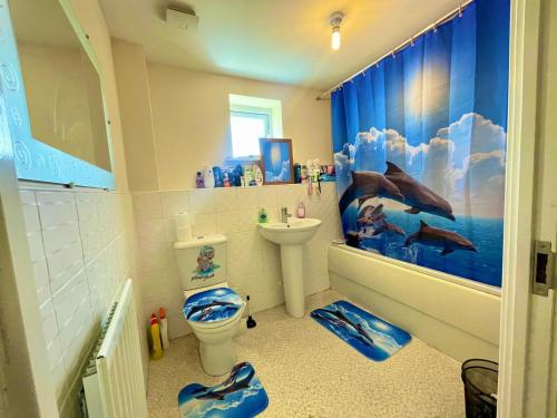 a bathroom with a dolphin shower curtain and a toilet at Spacious room with study table in Hatfield