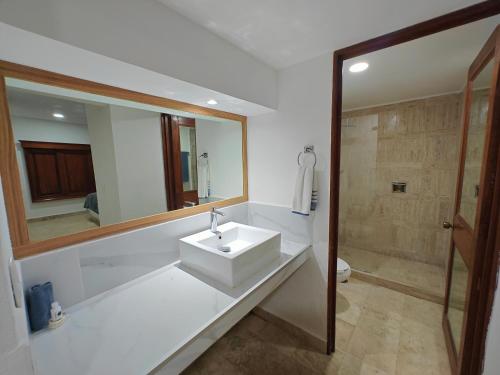 a white bathroom with a sink and a shower at Hotel Plaza Huatulco Bungalows in Santa Maria Huatulco