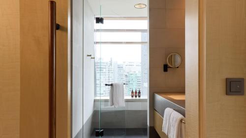a bathroom with a shower with a window and a sink at COMO Metropolitan Singapore in Singapore
