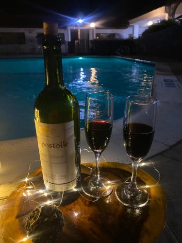 Una botella de vino y dos copas junto a una piscina en Hotel Villa Ricaurte, en Girardot