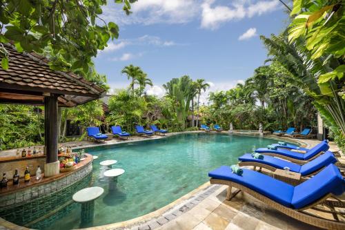 Tonys Villas & Resort Seminyak - Bali في سمينياك: وجود مسبح في المنتجع مع كراسي الصالة الزرقاء
