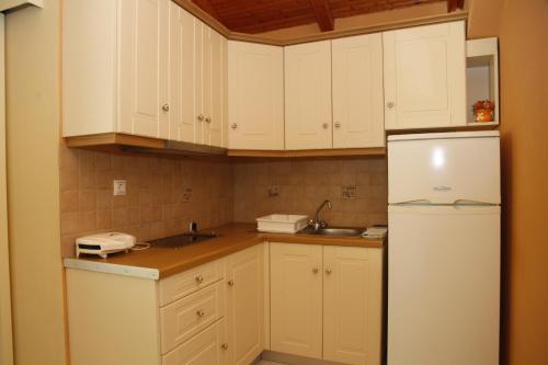 a kitchen with white cabinets and a white refrigerator at Ramona in Lourdata