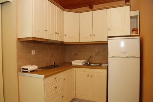 a kitchen with white cabinets and a white refrigerator at Ramona in Lourdhata