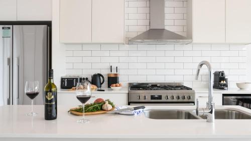 a white kitchen with a sink and two glasses of wine at Rock Cottage in Trentham