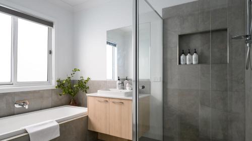 a bathroom with a tub and a sink and a shower at Rock Cottage in Trentham