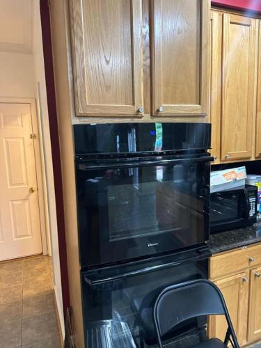 a black microwave in a kitchen with wooden cabinets at PEACE HOME(EVENTS ALLOWED) in Hughesville