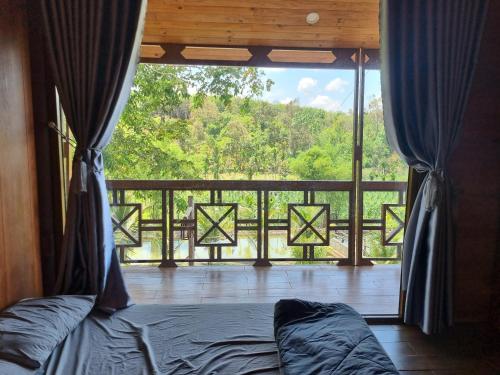 1 dormitorio con vistas a un balcón con cama en An Nhien Farm - Venuestay, en Buon Ma Thuot