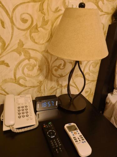 a table with a lamp and a clock and a remote control at Hotel Casa Divina Oaxaca in Oaxaca City