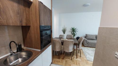 uma cozinha com uma mesa e cadeiras e um sofá em Apartman Veljković Zapadni Kej em Pirot