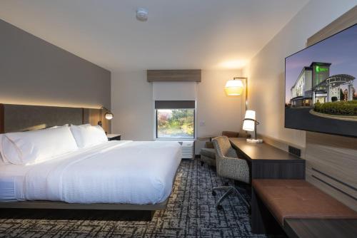 a hotel room with a bed and a desk and a television at Holiday Inn Anderson by IHG in Anderson