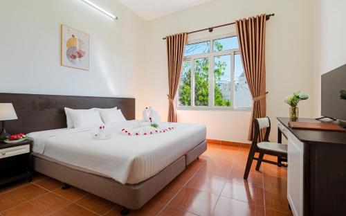 a bedroom with a bed and a desk and a window at BIDV Central Da Lat Hotel in Da Lat