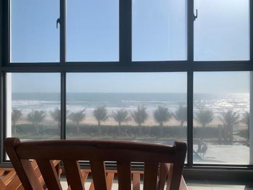 a window with a bench looking out at the beach at Bờ Biển Vàng Resort in Ke Ga