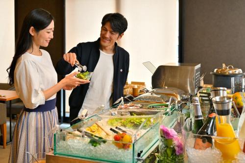 a man and a woman eating food at a buffet at KAYA Kyoto Nijo Castle, BW Signature Collection by Best Western in Kyoto