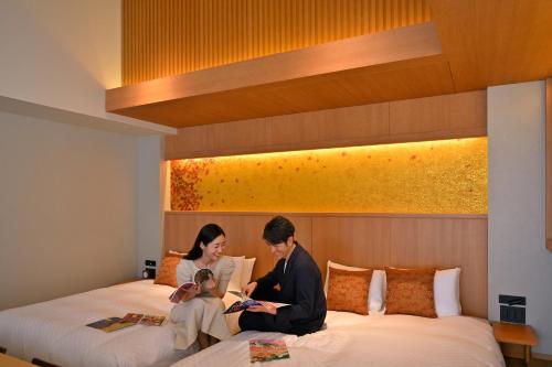 a man and woman sitting on a bed with a baby at KAYA Kyoto Nijo Castle, BW Signature Collection by Best Western in Kyoto