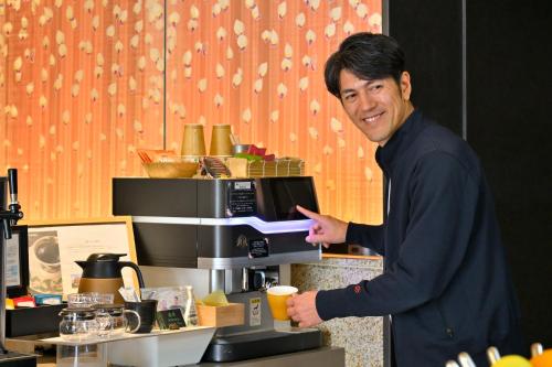 a man standing in front of a coffee machine at KAYA Kyoto Nijo Castle, BW Signature Collection by Best Western in Kyoto