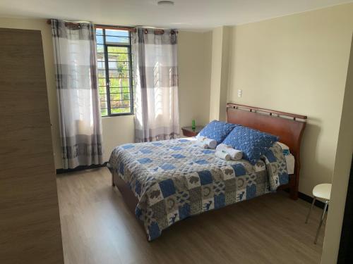 sypialnia z łóżkiem z niebieską kołdrą i oknem w obiekcie Casa campestre Boyacá, cerca a lugares turísticos w mieście Duitama