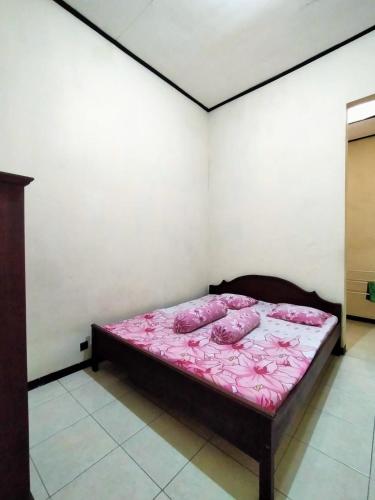 een slaapkamer met een bed met roze lakens en kussens bij Guest House Djatis Purwo Wasito in Bojonegoro