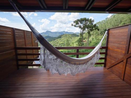 a hammock on a deck with a view of the mountains at Pousada Rural Altos de Lumiar in Nova Friburgo