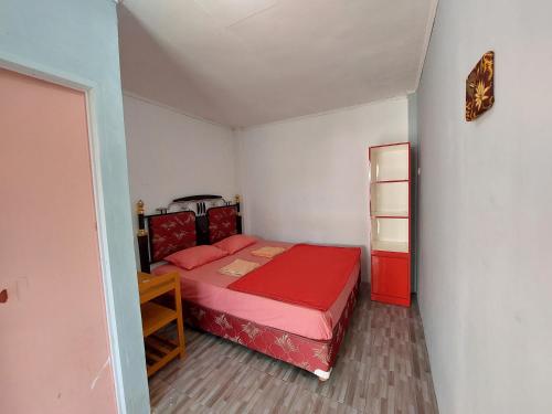 Un pequeño dormitorio con una cama roja en una habitación en Maharani Homestay, en Gorontalo