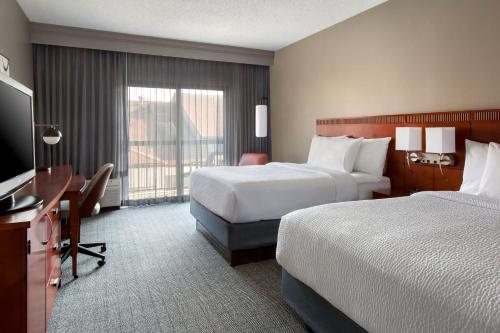 a hotel room with two beds and a desk at Courtyard by Marriott Tarrytown Westchester County in Tarrytown