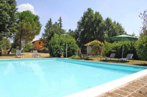 - une piscine avec 2 chaises et un parasol dans l'établissement Villa Ca Piero Urbino, à Urbino