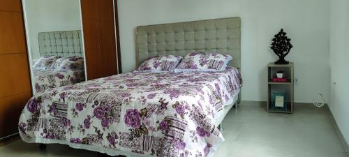 a bedroom with a bed with a floral bedspread and pillows at Onde a vida acontece in Salvador