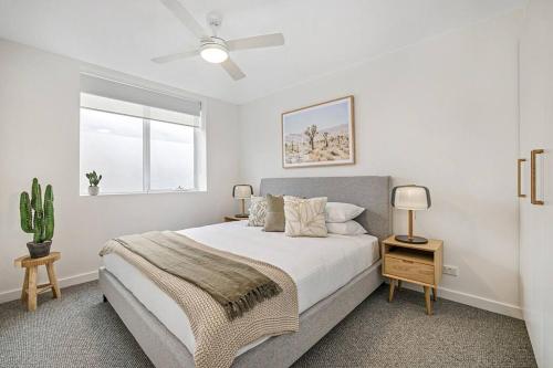 a white bedroom with a bed and a window at Stylish 2- Bedroom Unit near parks, shopping and dining in Melbourne