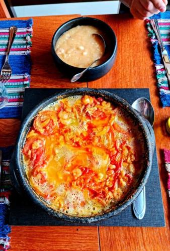 a pizza in a pan on a table with a bowl of soup at Pousada Rural Altos de Lumiar in Nova Friburgo