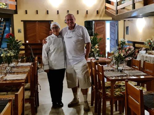 a man and a woman are standing in a restaurant at Pousada Rural Altos de Lumiar in Nova Friburgo