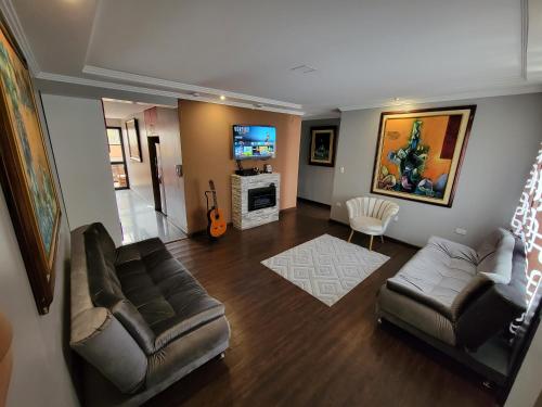 a living room with a couch and a tv at Departamento Duplex con Suite in Cuenca