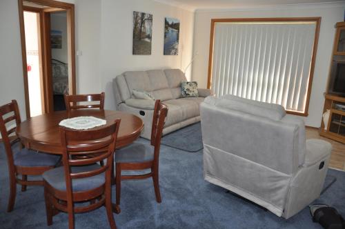 a living room with a couch and a table and chairs at Blue Wren Cottage in Tumut