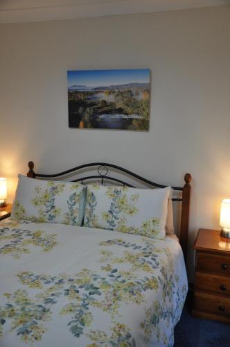 sypialnia z łóżkiem i obrazem na ścianie w obiekcie Blue Wren Cottage w mieście Tumut